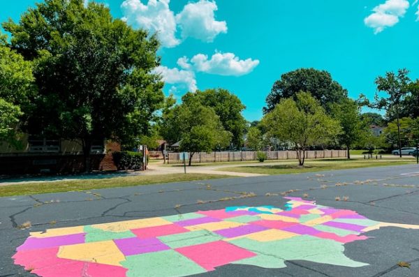 A parking lot with a map of the united states drawn in colorful chalk, with trees and park in the background